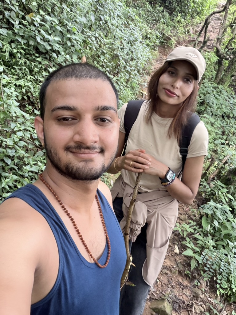The two of us on a green forest trail during our first hike, you holding a walking stick