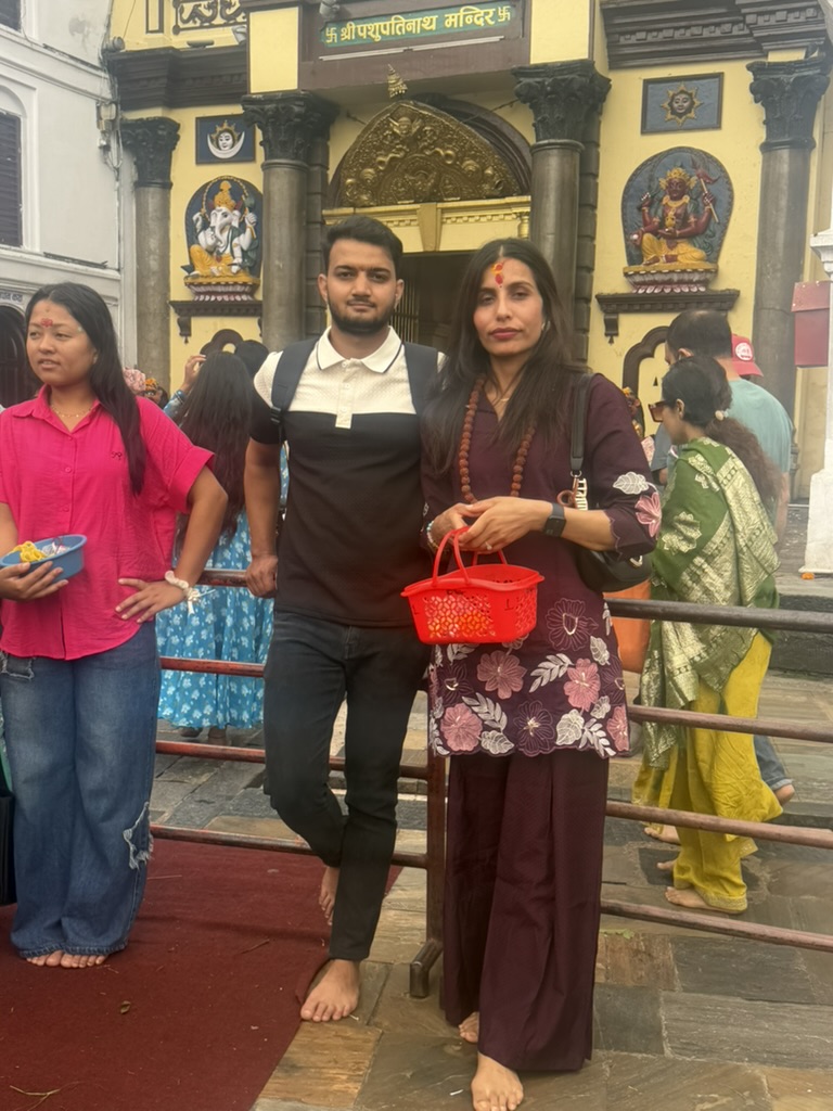 The two of us standing barefoot at the entrance of Pashupatinath temple, holding a red puja basket